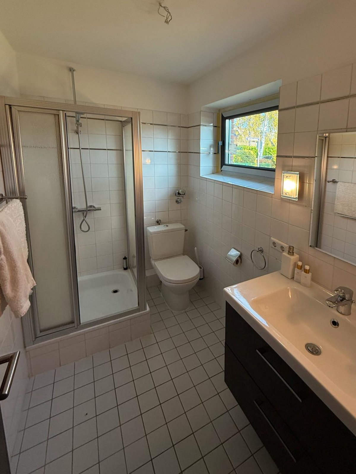 Gästebad vorher: weiß gefliestes Bad mit Duschkabine und Duschtasse, Stand-WC, Waschtisch mit dunklem Unterschrank und Spiegel