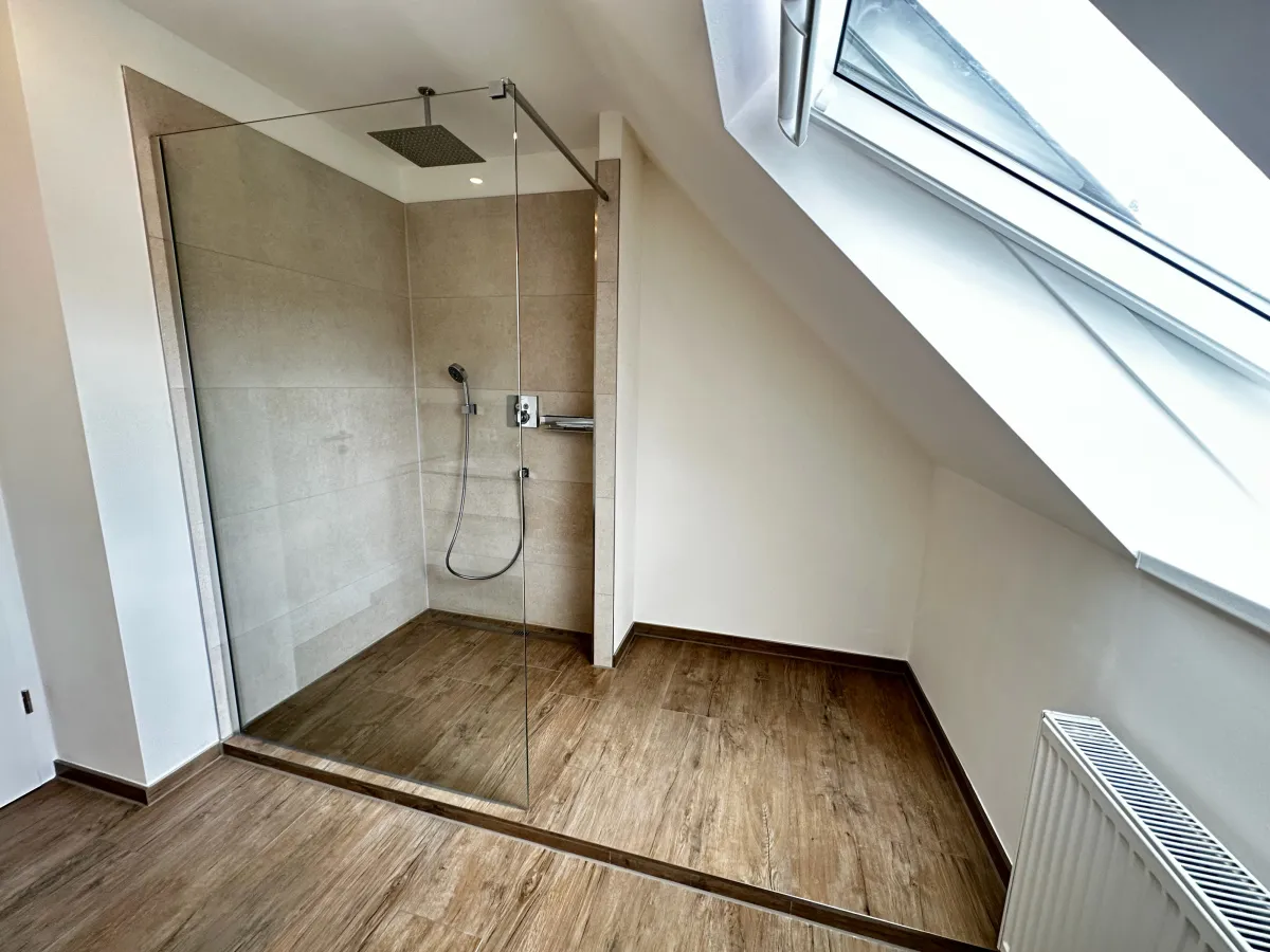 Bodengleiche Dusche mit Glaswand unter der Dachschräge, Boden in Holzoptik