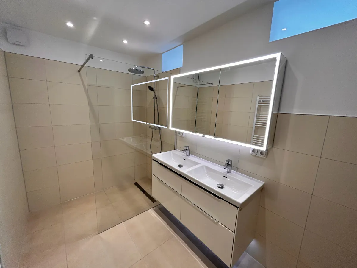 Bad mit Doppelwaschtisch, beleuchtetem Spiegelschrank und bodengleicher Dusche