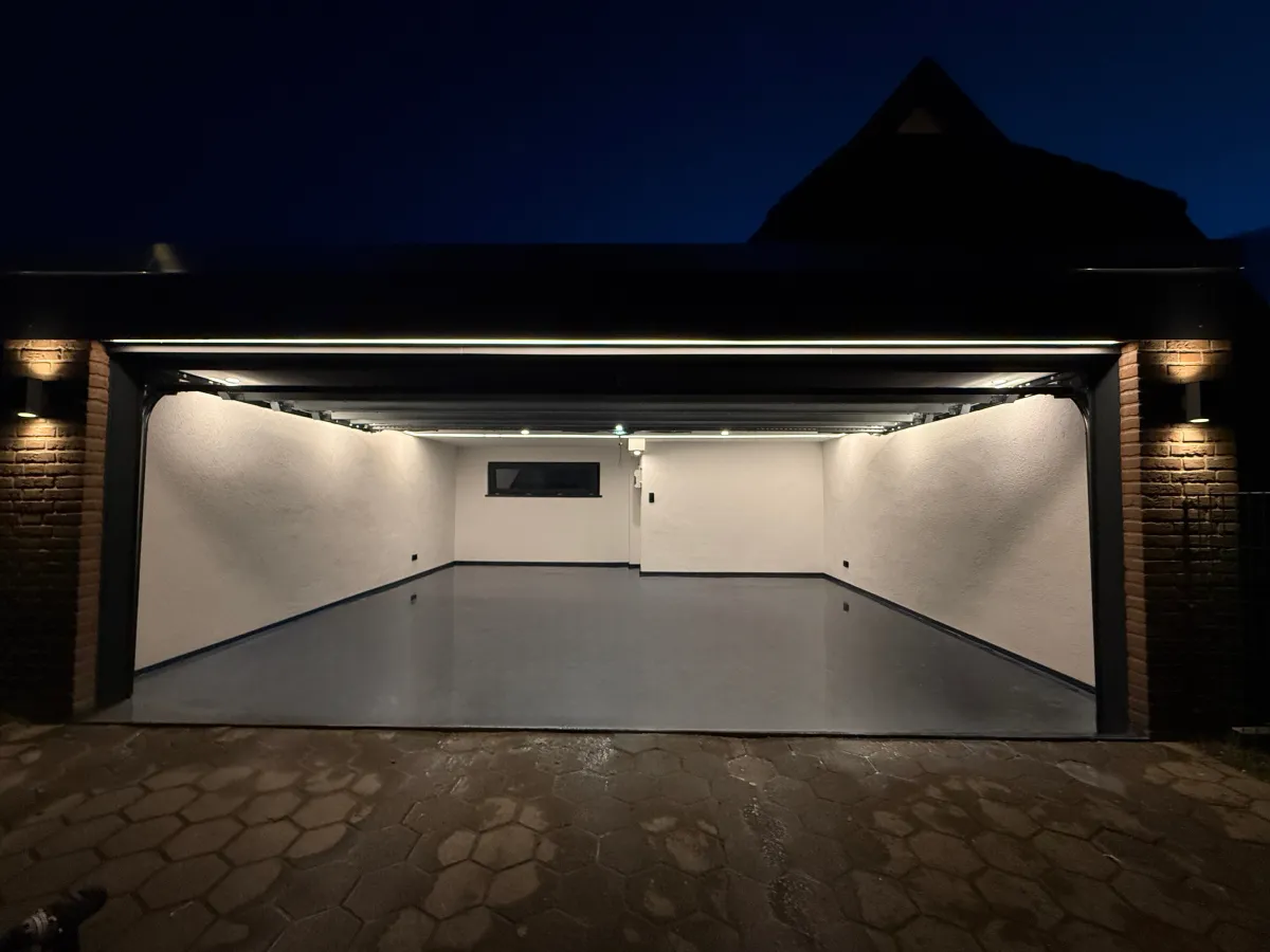 Garage mit hellen Wänden, grauem Boden und Lichtleisten