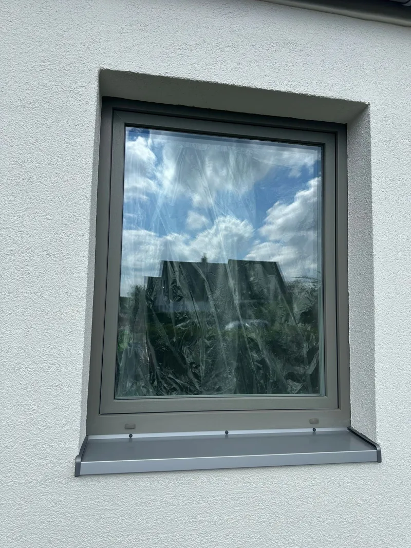 Fenster mit Fensterbank in der neu verputzten Fassade