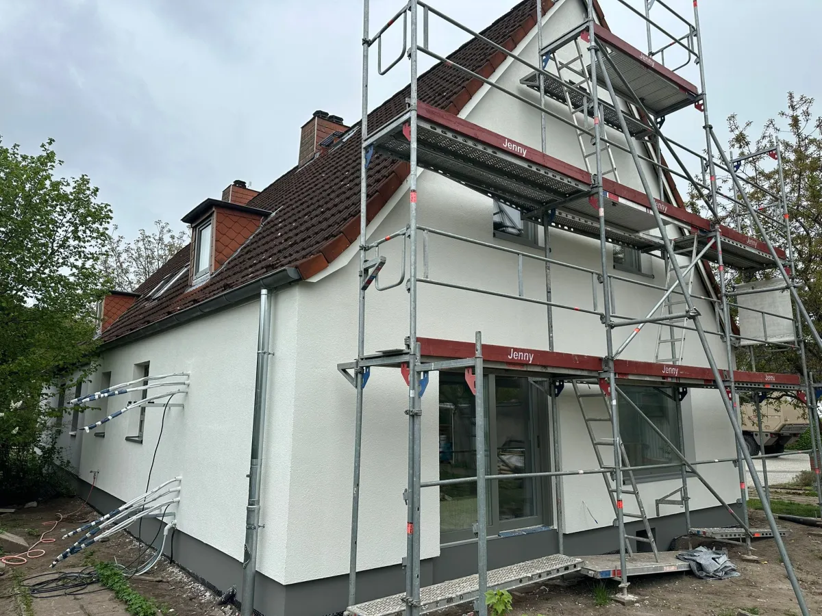 Haus mit Gerüst und frisch verputzter, heller Fassade während der Sanierung