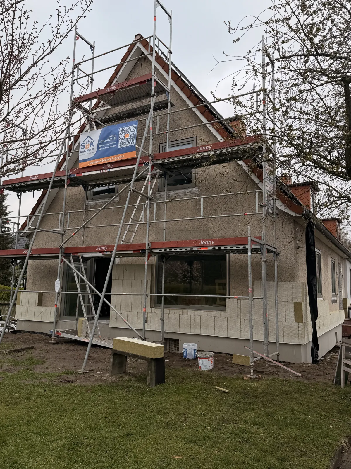 Giebelhaus mit Gerüst und Dämmplatten während der Fassadensanierung