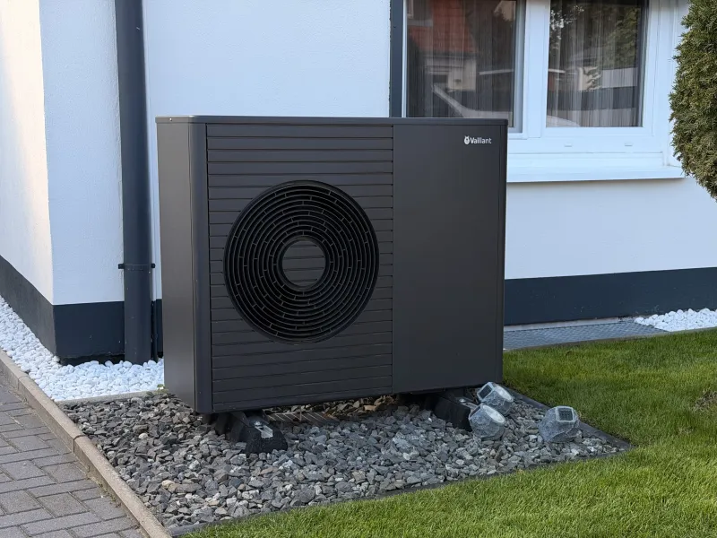 Außengerät einer Wärmepumpe auf einem Kiesbett vor dem Haus